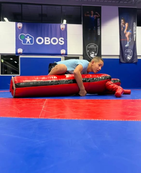 Young athlete in plank position on red foam roller during training at OBOS gym facility
