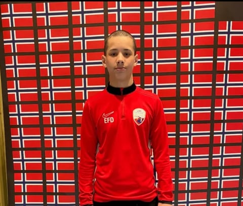 Person wearing red EFD sports jacket standing in front of Norwegian flag background