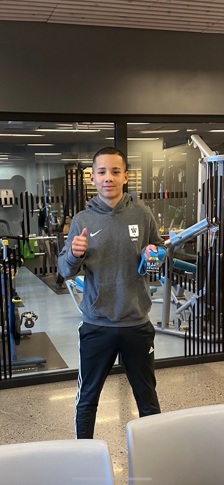Young person in gray Nike hoodie and black pants giving thumbs up inside a sports equipment retail store